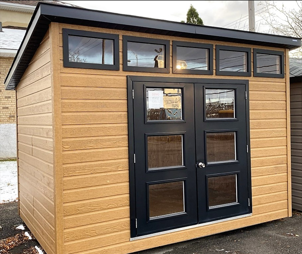 Cabanon en bois clair avec porte double noire vitrée et fenêtres horizontales en hauteur